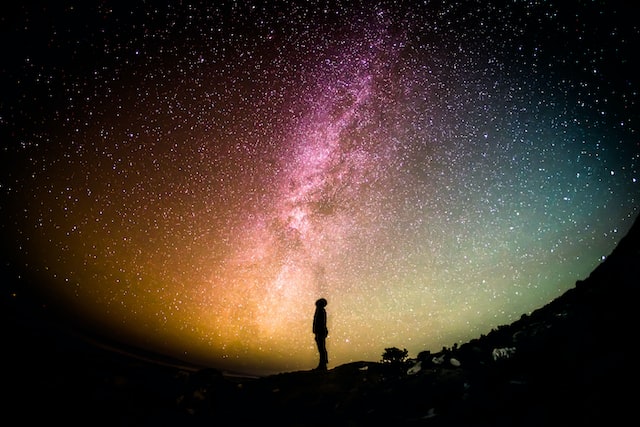 man hillside milkeyway sky stars universe heavens Photo by Greg Rakozy on Unsplash