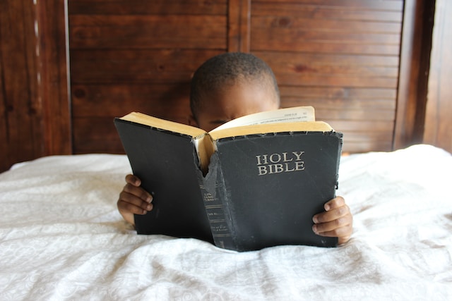 Child in bed reading the bible - christian -